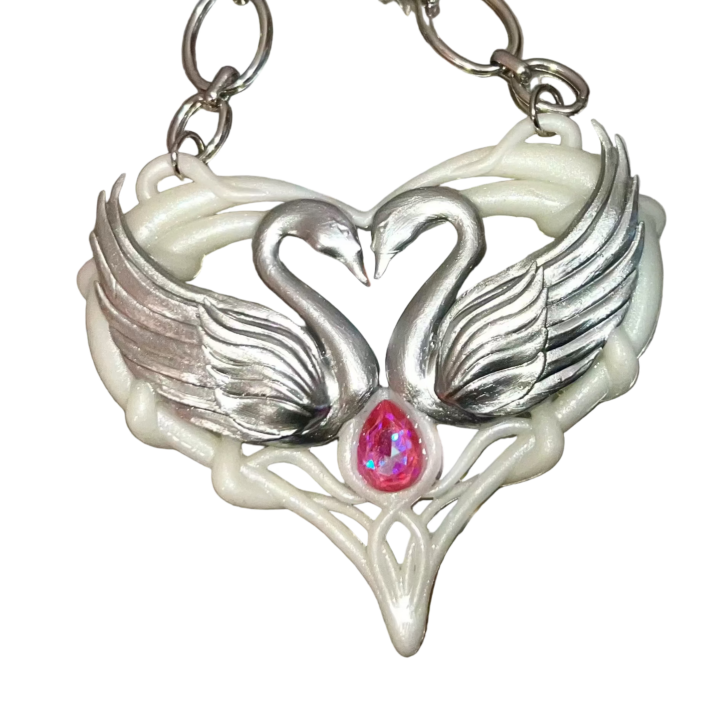 Silver necklace with a heart-shaped pendant featuring two swans and a pink gemstone on a metallic surface.