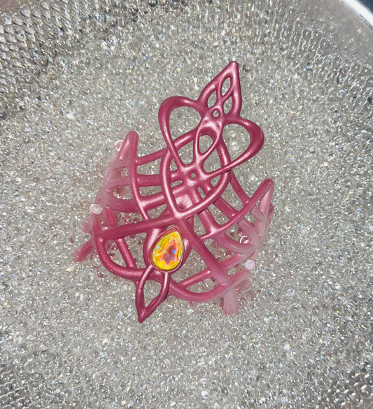Pink decorative item with a yellow center on a reflective surface